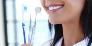Woman holding dental tools and toothbrush.